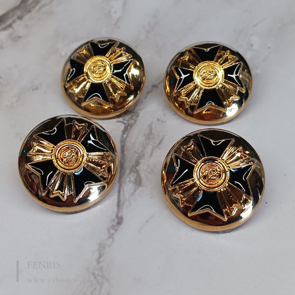 Four gold and black decorative buttons on a marble surface
